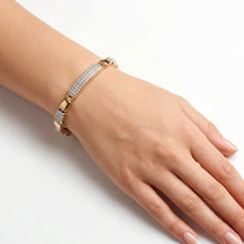Load image into Gallery viewer, A gold-plated bracelet with pavé-set clear stones worn on a person's wrist, shown against a clean white background.
